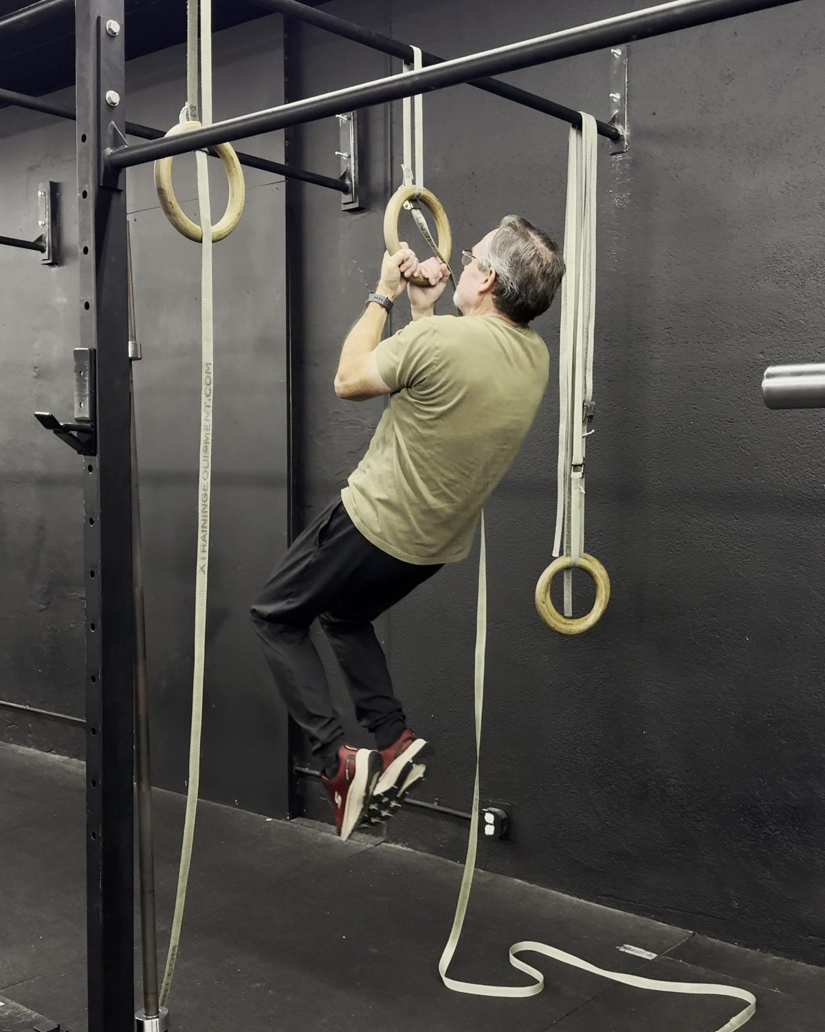 Dave, a NW FIT member in his 70s, pulling himself up to the top of a chin-up on gymnastic rings